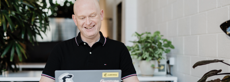 Smiling man sending an email on his laptop